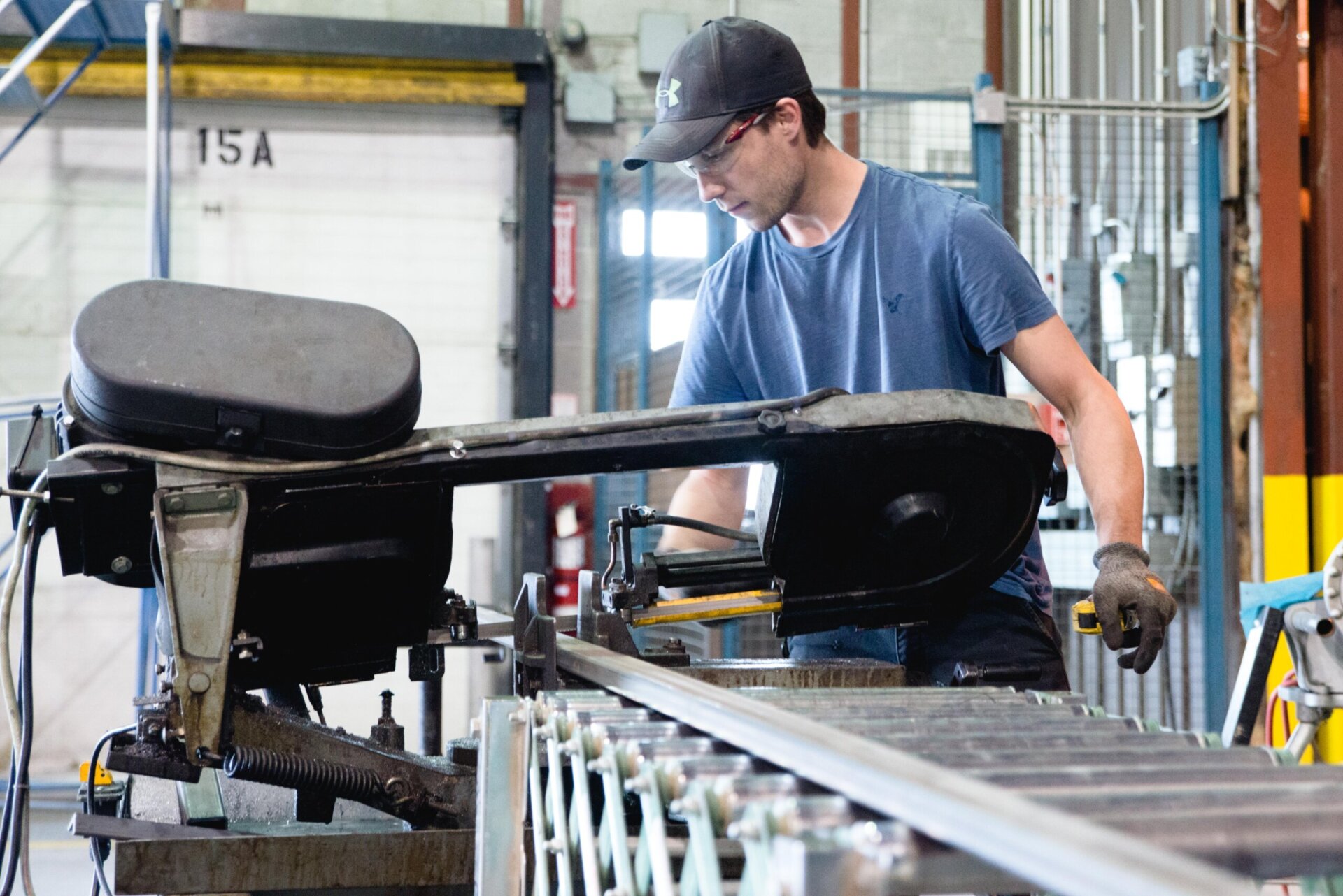 An assembly technician works with power cutting machinery to cut length steel to create components at a Newterra plant in Brockville