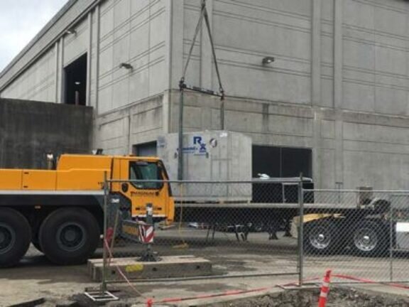 A crane lifts a Clara filter concrete box from delivery trailer at an industrial site