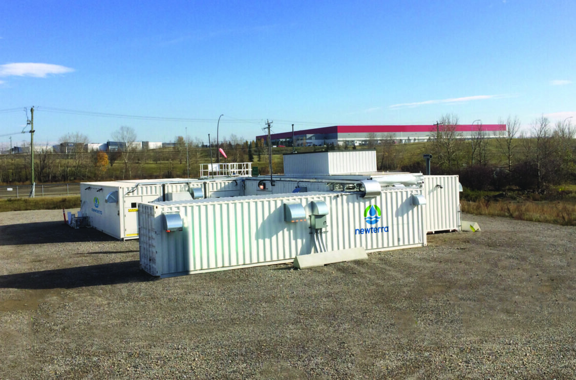 Three modular wastewater treatment technology units are oriented in a U shape near an industrial district of a medium sized metropolitan area