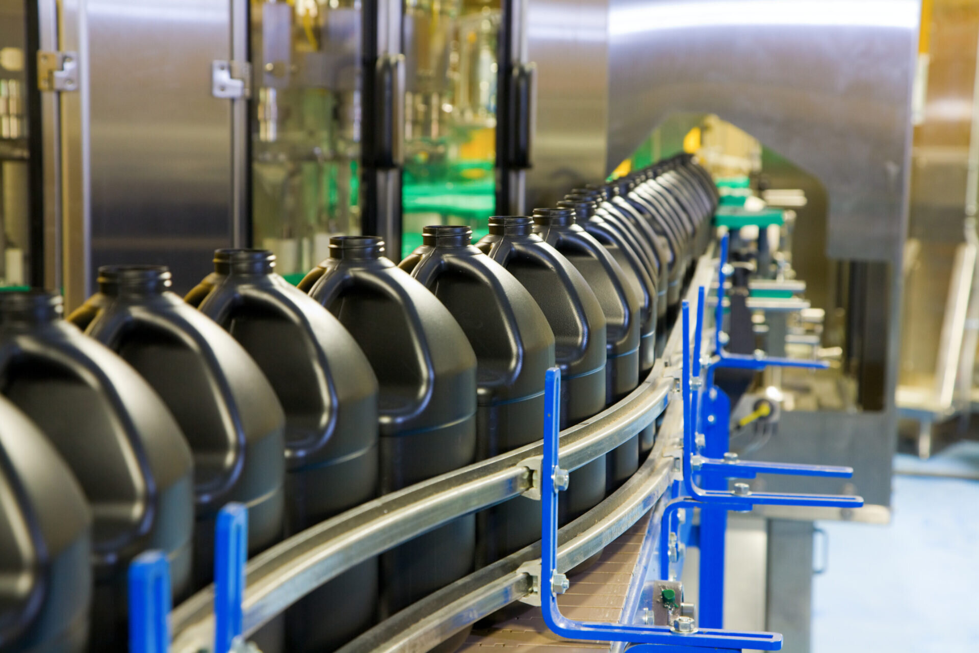 Black plastic handled jugs traverse and assembly line prior to being filled