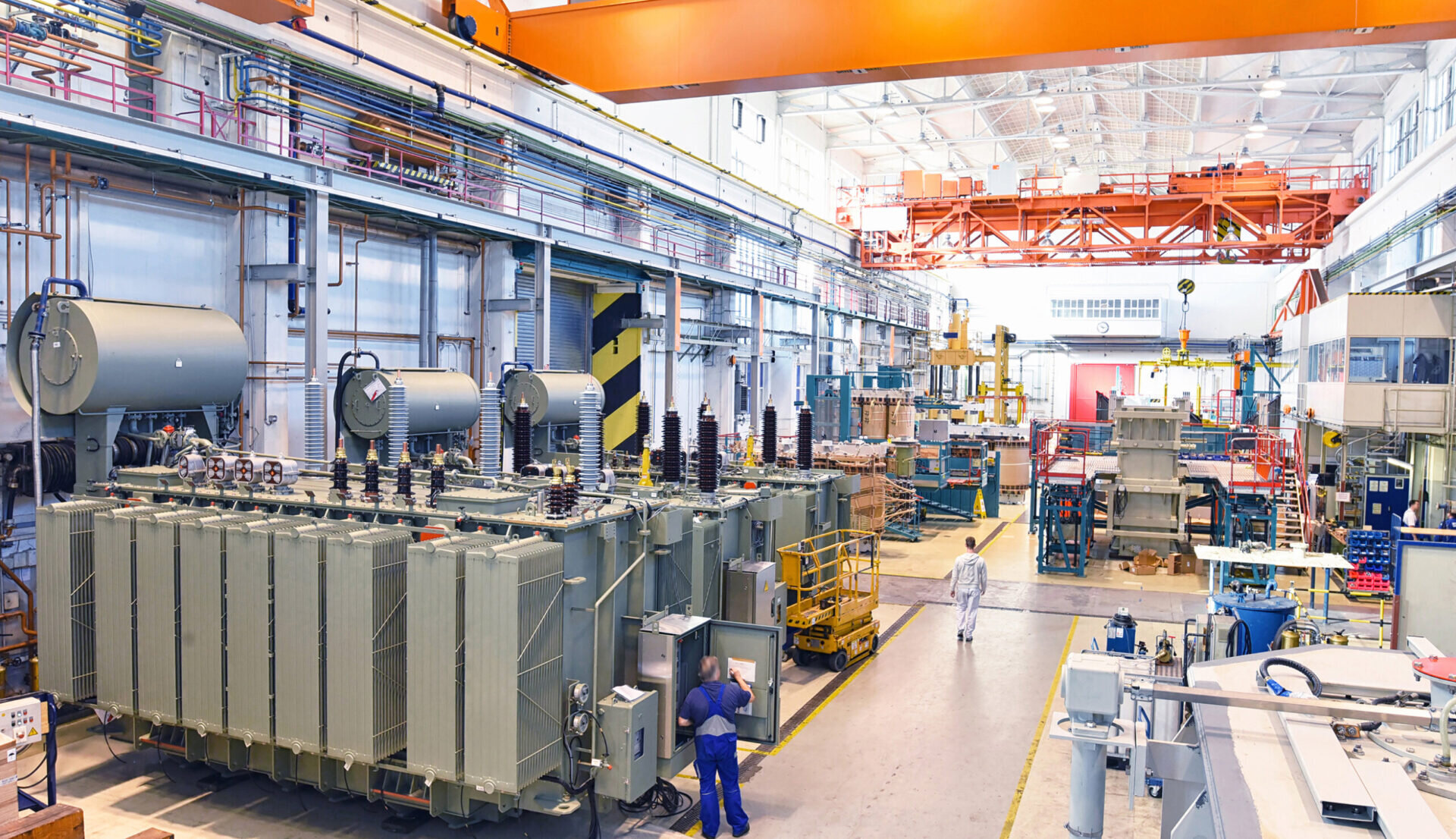 An interior view of a manufacturing plant with large power inverters twice as tall as an average person