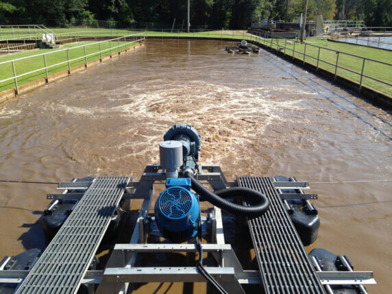 Stationary aerator treatment solution outdoors consisting of a rectangular holding pond protected by guard rails aerates water