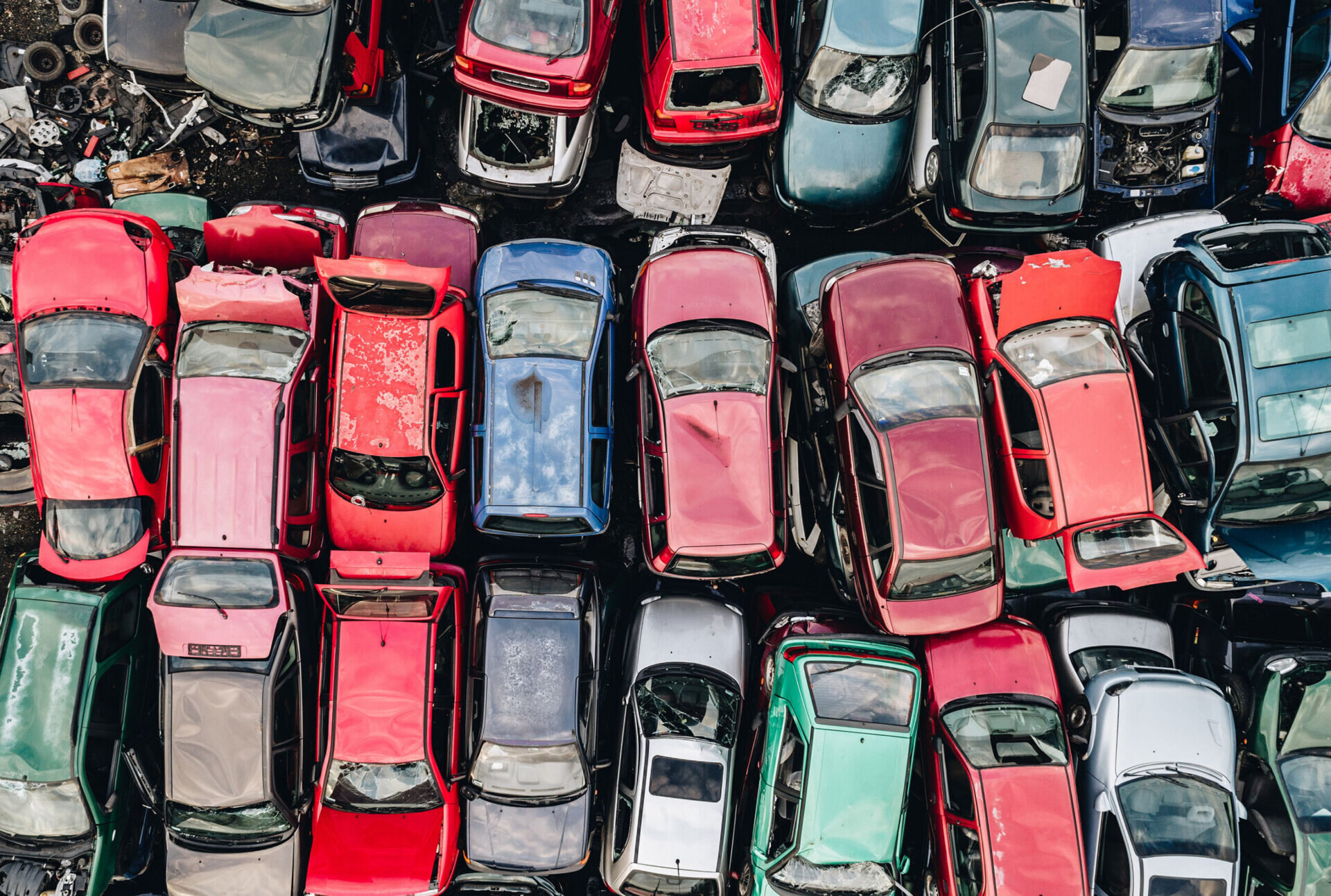 Collection of primarily red vehicles are stacked for recycling