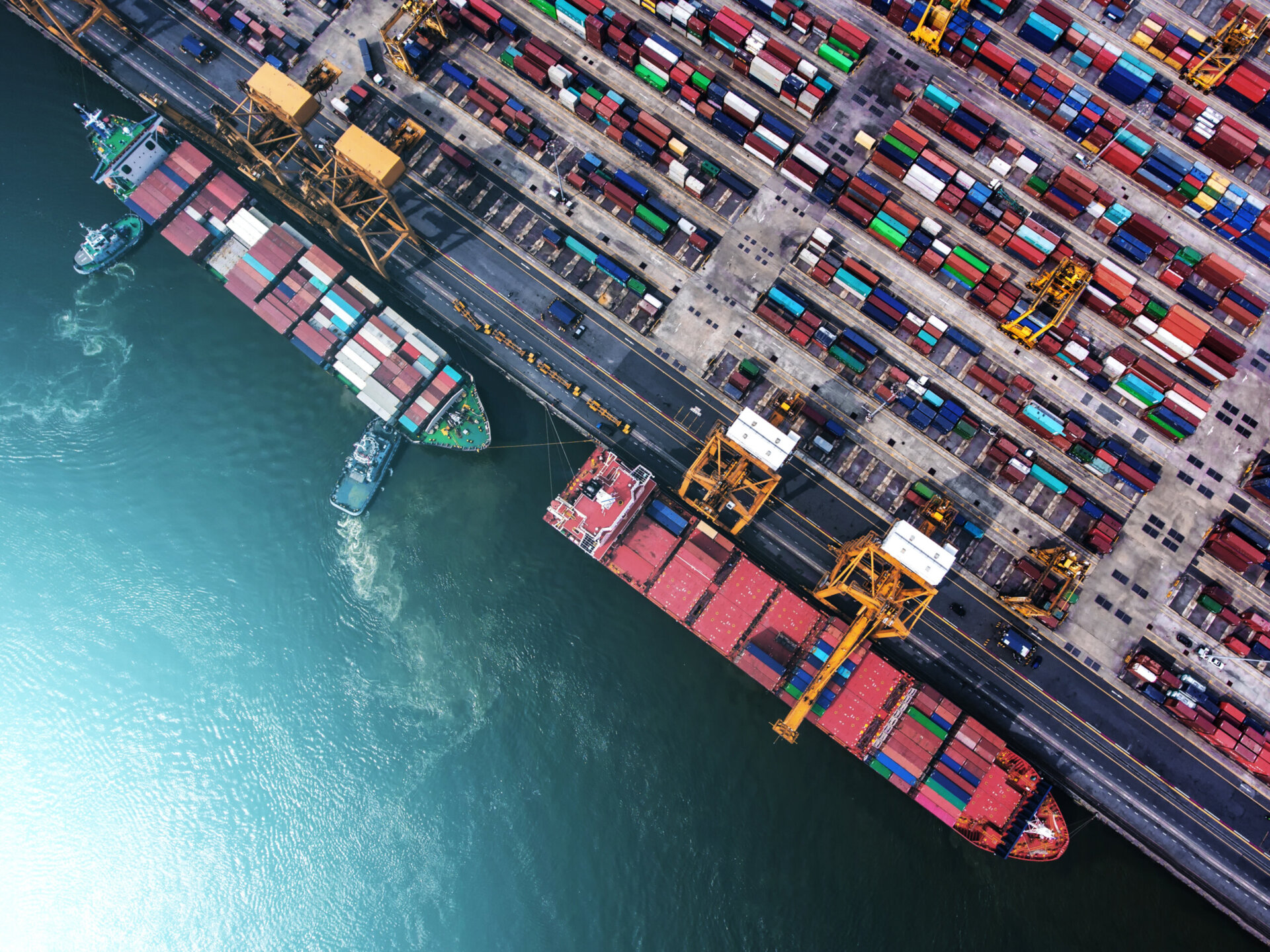 Two cargo ships arrive at a port filled with shipping containers