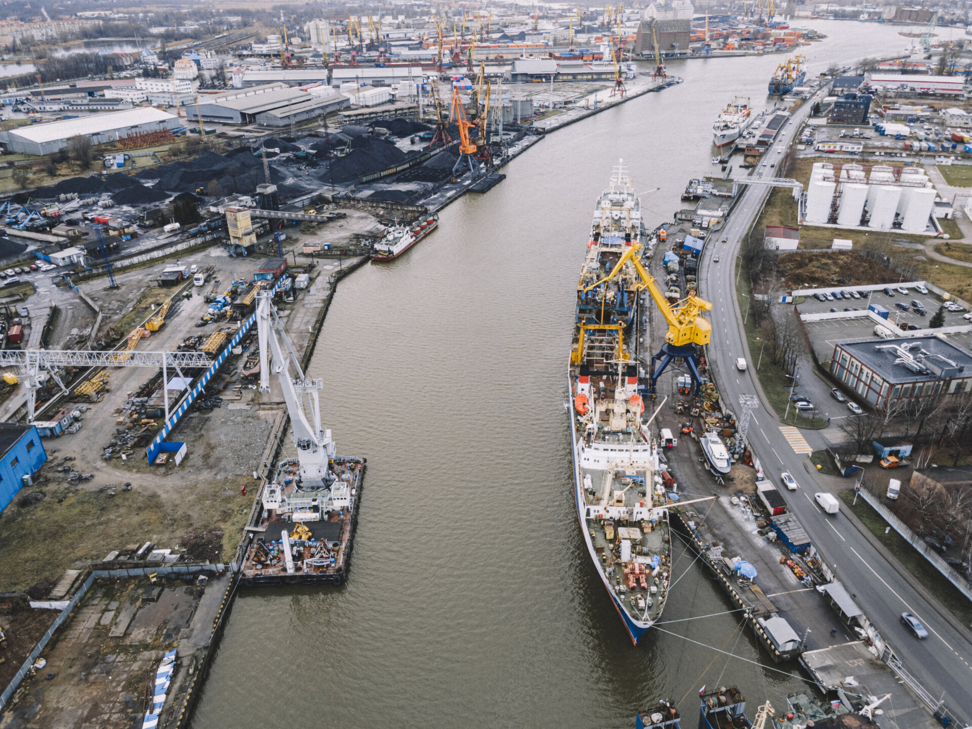 A big blue ship and yellow cranes on the water in the port of an industrial city. Cargo transportation by sea. concept. top view, aerial view