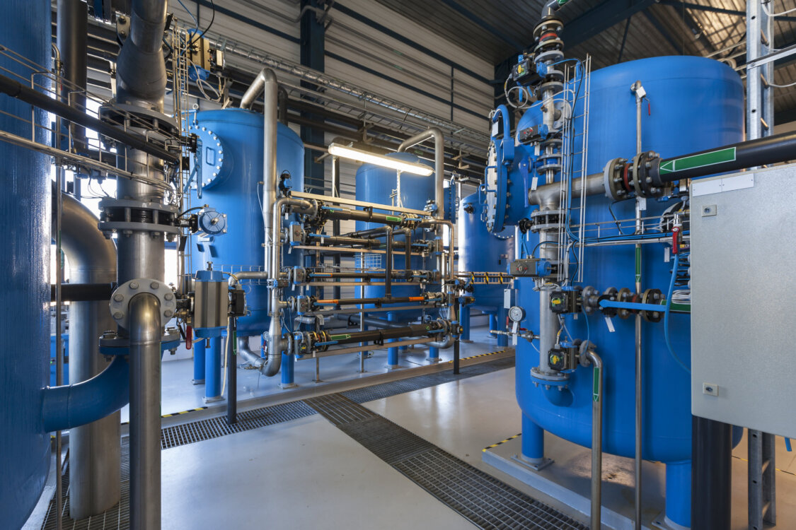 Industrial massive water filtering machinery including multiple elevated blue tanks connected by steel pipes