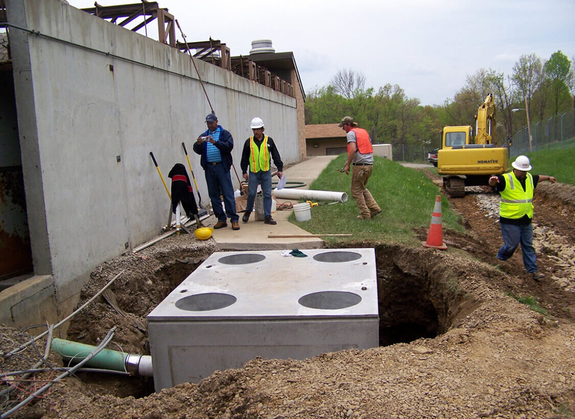 Three technicians and a manager install a Clara Gravity Separator from Newterra at a new construction site for industrial use