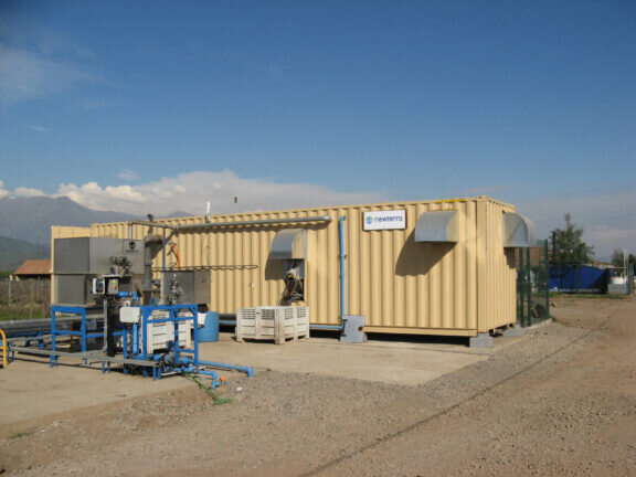 Pale yellow shipping container modular food and beverage water treatment solution sits outdoors on a concrete slab