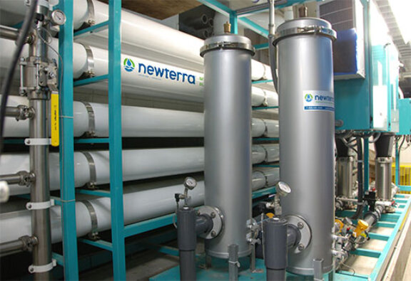 Newterra boiler feed system with five stacked plastic pipes with steel water cooling treatment pipes in an industrial application