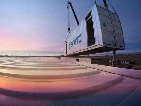 Newterra container being lowered onto a site with a sunset in the background