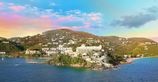 A resort on a cliff overlooking the ocean with a sunset in the background